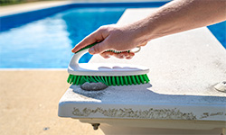 Person using scrub brush to clean diving board