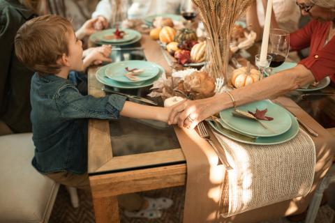 A family holds hands around a table at Thanksgiving dinner