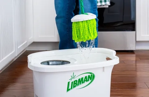 A white libman mop bucket that is on the ground in a kitchen.